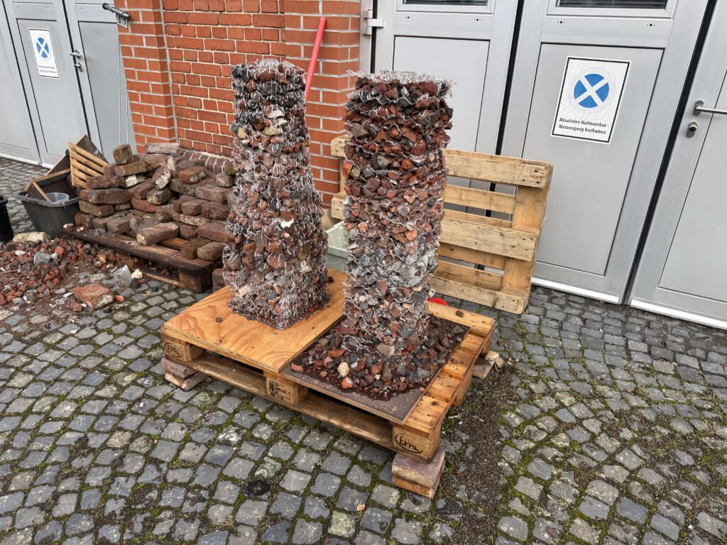Two column prototypes: robotically printed plastic lattice filled with brick rubble